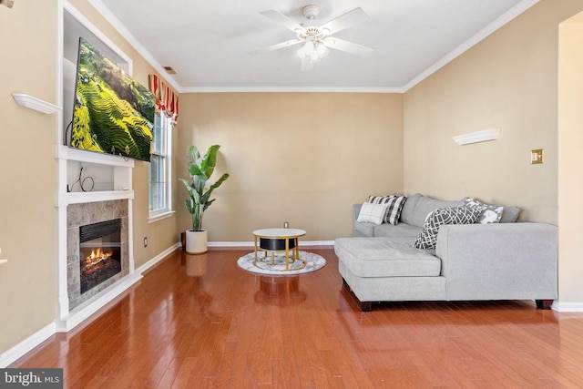 living room with ornamental molding, baseboards, wood-type flooring, and ceiling fan