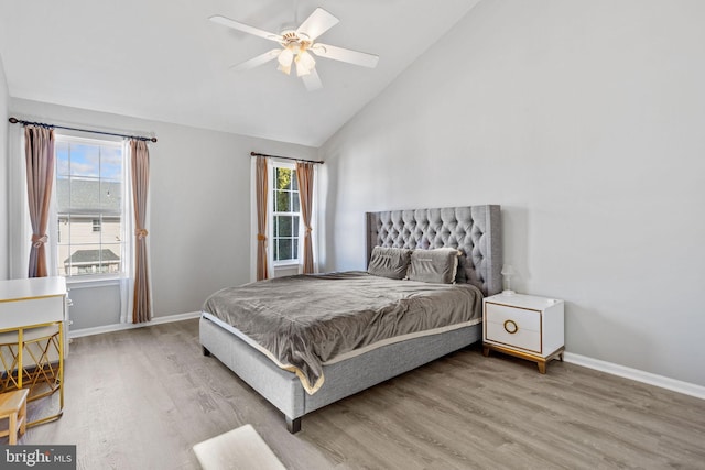 bedroom featuring baseboards, multiple windows, wood finished floors, and vaulted ceiling