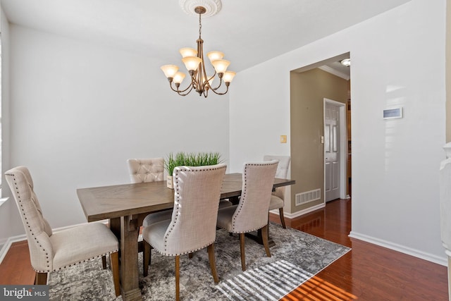 dining space with visible vents, baseboards, an inviting chandelier, and wood finished floors