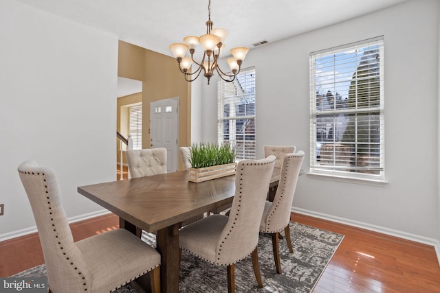 dining area with a notable chandelier, baseboards, visible vents, and wood-type flooring