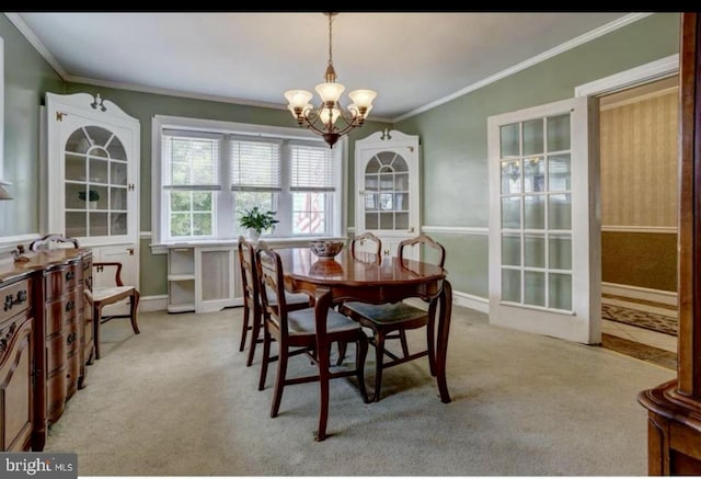 carpeted dining room with a chandelier, baseboards, and ornamental molding