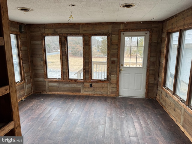 interior space with wooden walls, dark wood-style floors, and visible vents