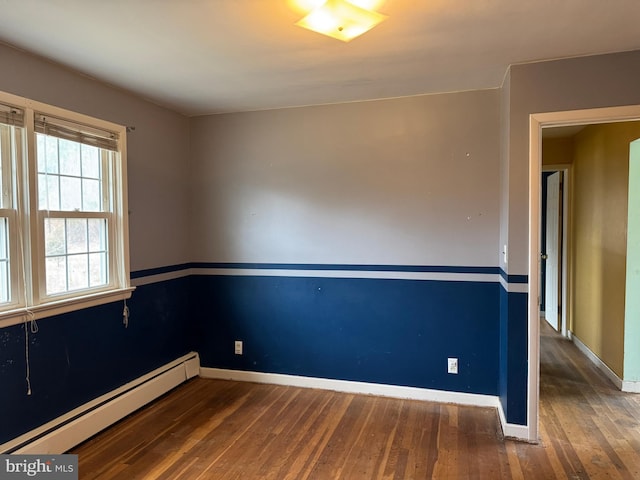 spare room with a baseboard radiator, baseboards, and hardwood / wood-style flooring