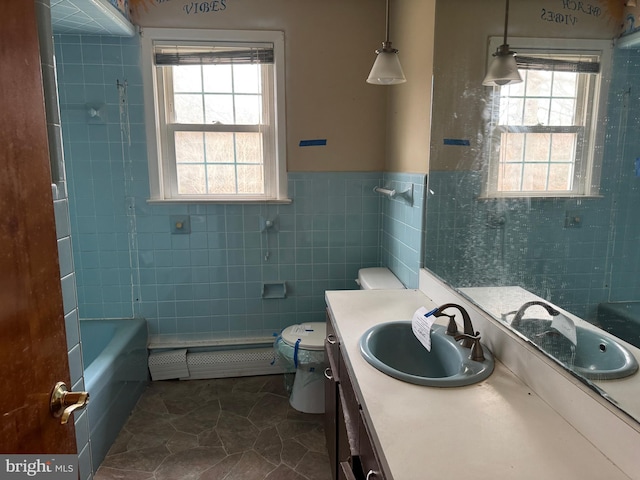 bathroom with vanity, tile walls, toilet, baseboard heating, and a washtub