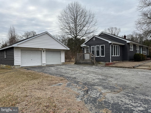 view of front of home featuring a detached garage, an outdoor structure, and a chimney