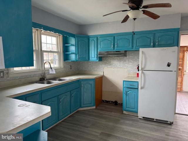 kitchen featuring a sink, blue cabinetry, under cabinet range hood, freestanding refrigerator, and ceiling fan