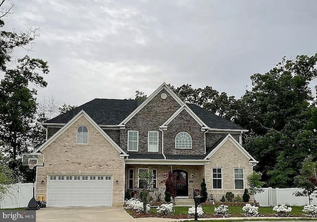 traditional-style house with driveway, stone siding, fence, an attached garage, and a front yard