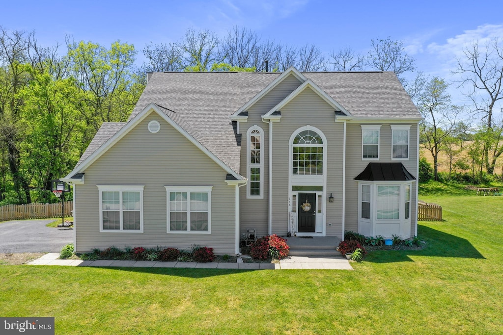 view of front of home featuring roof with shingles, a front yard, and fence