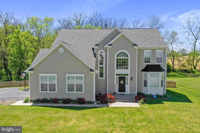 view of front of home featuring roof with shingles, a front yard, and fence