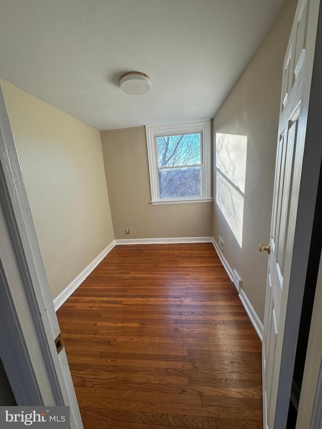 spare room featuring baseboards and dark wood finished floors