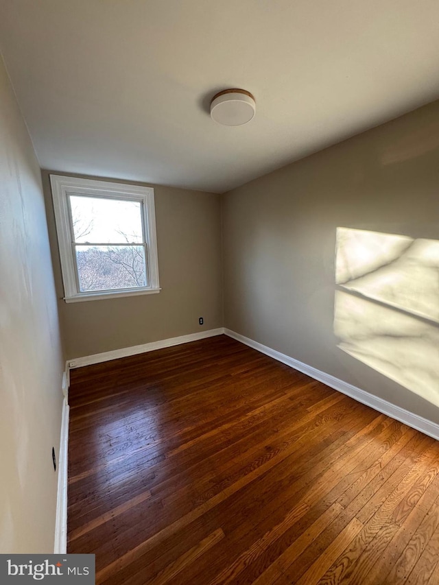 empty room with baseboards and dark wood-style floors