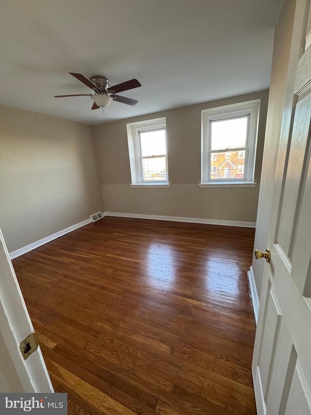 unfurnished room featuring visible vents, ceiling fan, dark wood-type flooring, and baseboards