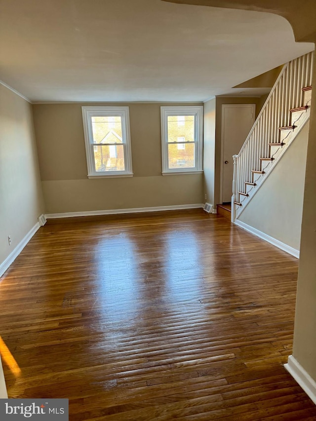 empty room featuring stairs, baseboards, and dark wood-style flooring