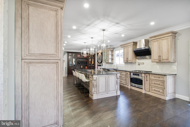 kitchen featuring a kitchen bar, tasteful backsplash, wall chimney exhaust hood, crown molding, and stainless steel oven