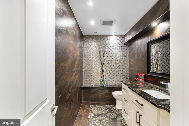 bathroom with visible vents, toilet, vanity, recessed lighting, and tile walls