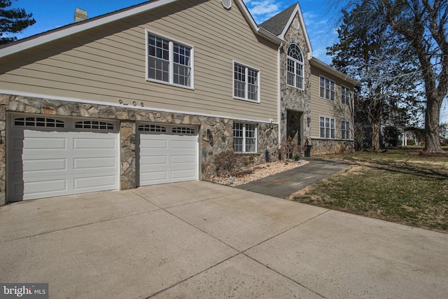 view of front of home with an attached garage, stone siding, and driveway