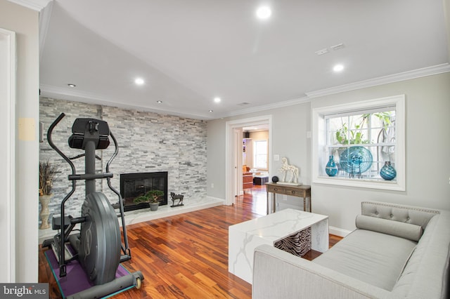 living area featuring baseboards, ornamental molding, a stone fireplace, recessed lighting, and wood finished floors