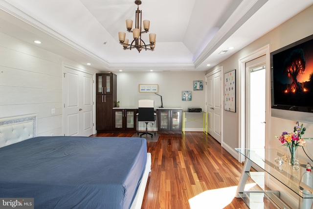 bedroom featuring baseboards, a tray ceiling, recessed lighting, wood finished floors, and a notable chandelier