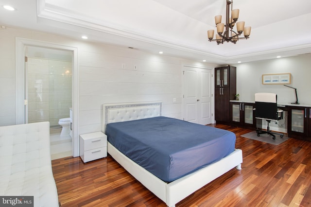 bedroom with wood finished floors, recessed lighting, a raised ceiling, a notable chandelier, and connected bathroom