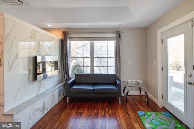 living area featuring a wealth of natural light, visible vents, wood-type flooring, and baseboards