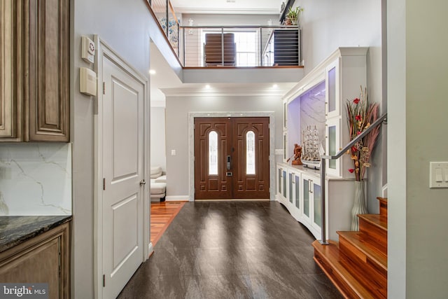 entryway featuring crown molding, baseboards, stairs, recessed lighting, and a towering ceiling