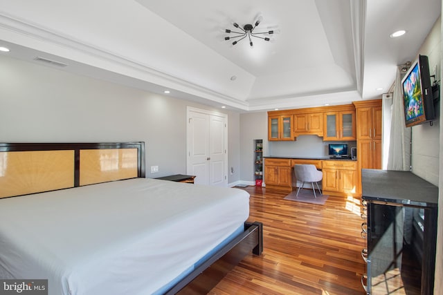 bedroom featuring visible vents, a tray ceiling, recessed lighting, light wood-style flooring, and built in study area