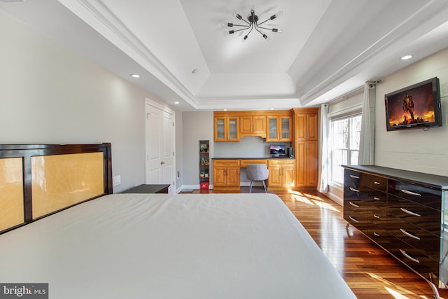 bedroom featuring recessed lighting, a raised ceiling, wood finished floors, and built in study area