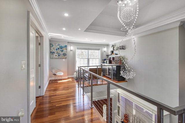 corridor with hardwood / wood-style floors, recessed lighting, ornamental molding, an upstairs landing, and a chandelier