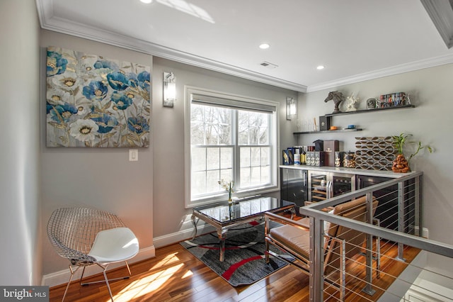 living area featuring visible vents, wood finished floors, baseboards, and ornamental molding