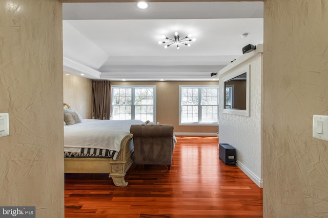 bedroom featuring baseboards, wood finished floors, a tray ceiling, an inviting chandelier, and a textured wall