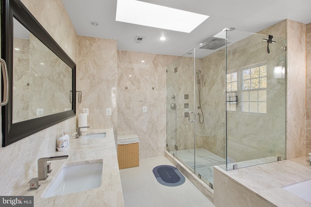 bathroom featuring tile walls, a skylight, a shower stall, and a sink