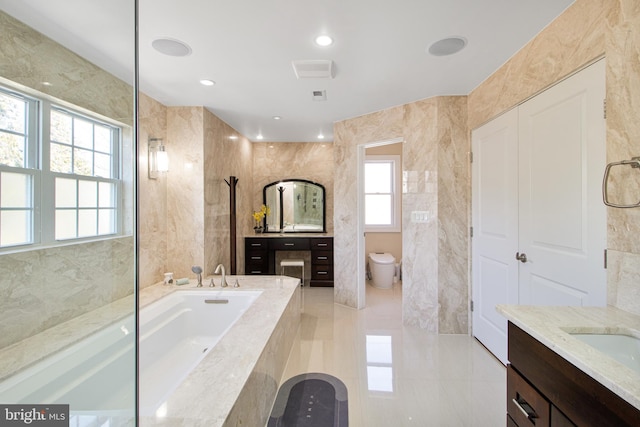 bathroom with a garden tub, toilet, recessed lighting, tile walls, and vanity