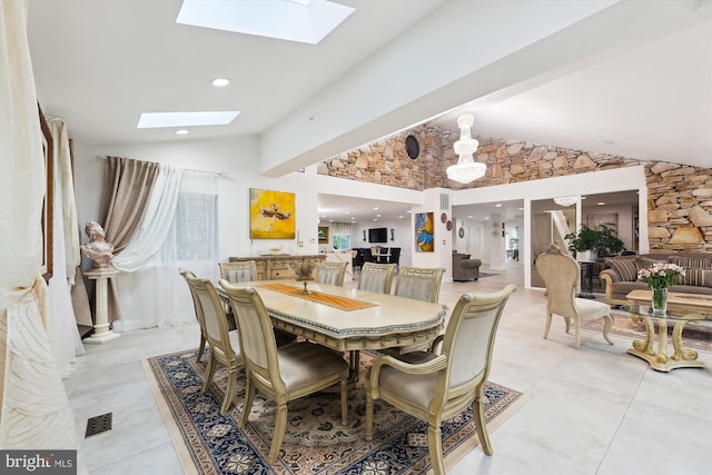 dining space featuring light tile patterned floors, visible vents, and vaulted ceiling with skylight