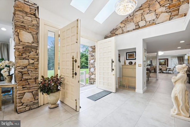 foyer entrance featuring a skylight, recessed lighting, high vaulted ceiling, and a chandelier