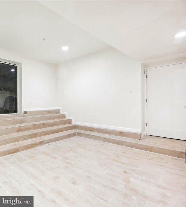 spare room featuring stairway, recessed lighting, baseboards, and wood finished floors