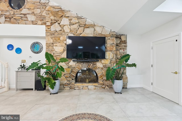 living room featuring a stone fireplace, lofted ceiling, baseboards, and tile patterned floors