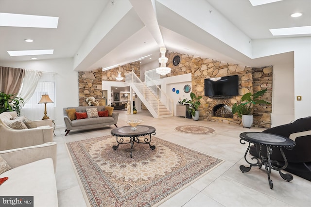 tiled living area featuring lofted ceiling with skylight, a stone fireplace, and stairs