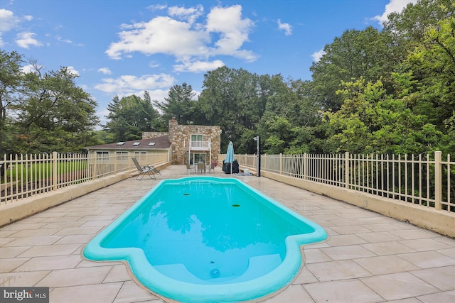 view of pool with an outdoor structure, a patio area, a fenced in pool, and a fenced backyard