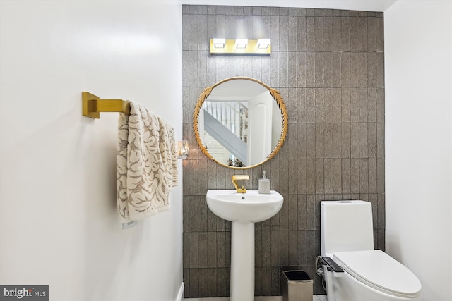 bathroom with toilet and tile walls