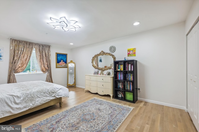 bedroom with recessed lighting, wood finished floors, baseboards, and a closet