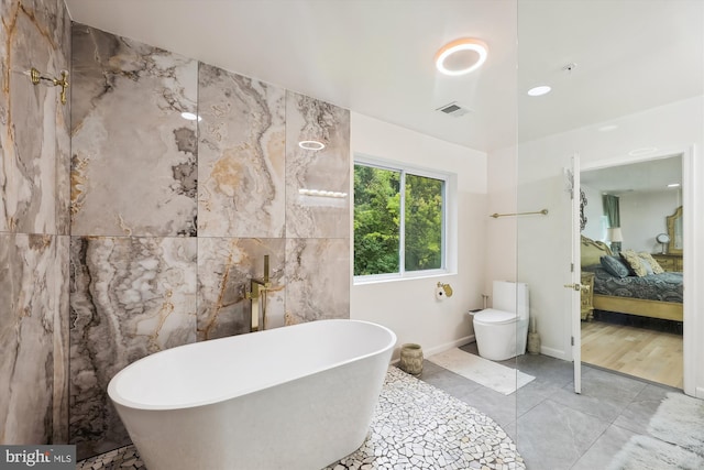 ensuite bathroom with visible vents, ensuite bath, a freestanding bath, tile walls, and toilet