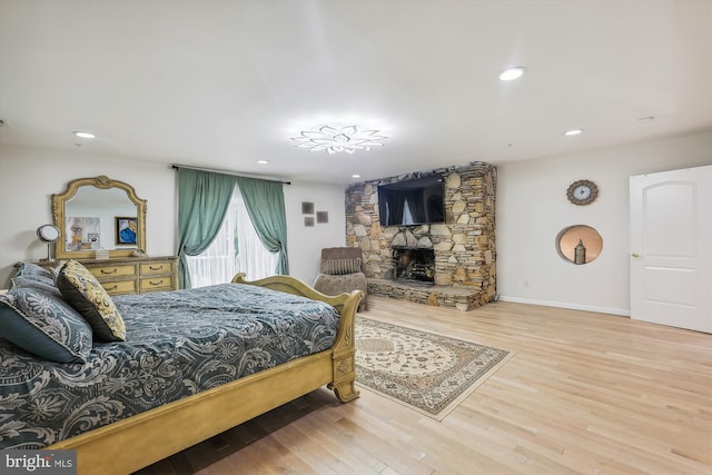 bedroom with recessed lighting, wood finished floors, and a fireplace