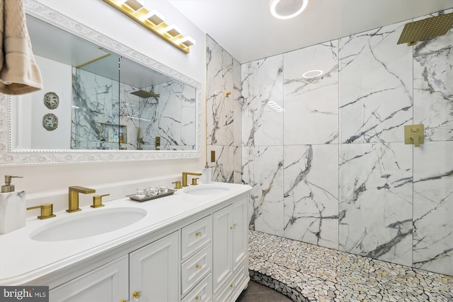 bathroom featuring a marble finish shower, double vanity, and a sink