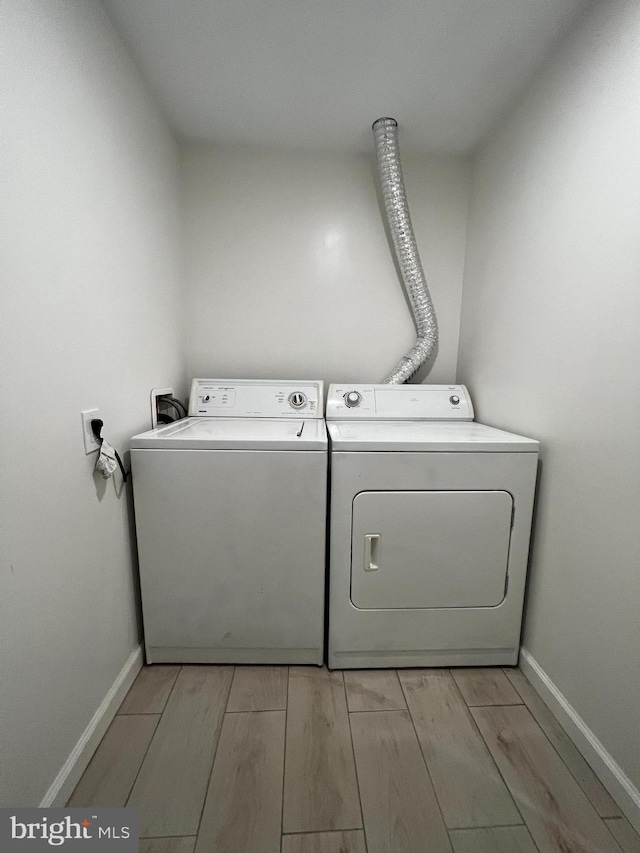 washroom with laundry area, wood tiled floor, baseboards, and washing machine and clothes dryer