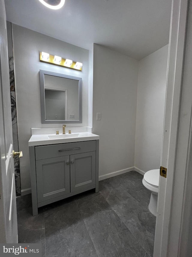 bathroom with toilet, vanity, and baseboards