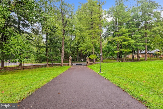 surrounding community with a yard, fence, aphalt driveway, and a gate