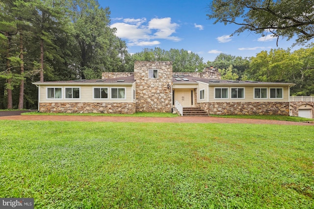 view of front of house featuring stone siding, a chimney, and a front yard