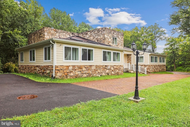 view of front of property with a front lawn, stone siding, and a chimney