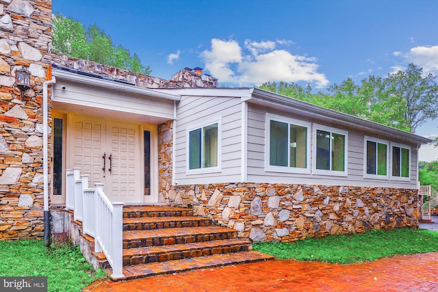 entrance to property with stone siding and a chimney