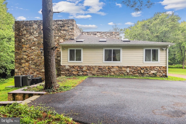 view of property exterior with stone siding and central AC unit